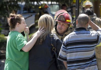 
Spokane Fire Department Lt. Mike Giampetri gets information from Carrie King, center, as she is consoled by her friend Kim Moser on Friday after the building where King lives caught fire Friday afternoon. 
 (Dan Pelle / The Spokesman-Review)