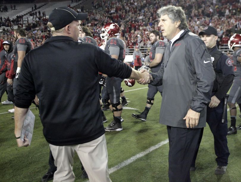 Washington State head coach Mike Leach, right, and Idaho head coach Paul Petrino shake hands in a chilly postgame meeting after the Cougars beat the Vandals 42-0 in 2013. (Dean Hare / Associated Press)