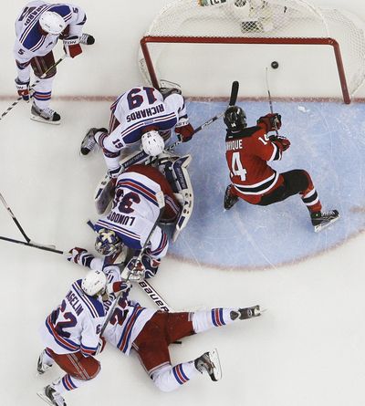 New Jersey Devils’ Adam Henrique, right, scores winning goal in overtime victory over the New York Rangers on Friday. (Associated Press)