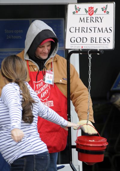 Salvation Army second-year bell ringer David Ruskey pats dollar bills into his red kettle at the Spokane Valley Wal-Mart, Monday. (J. Bart Rayniak)