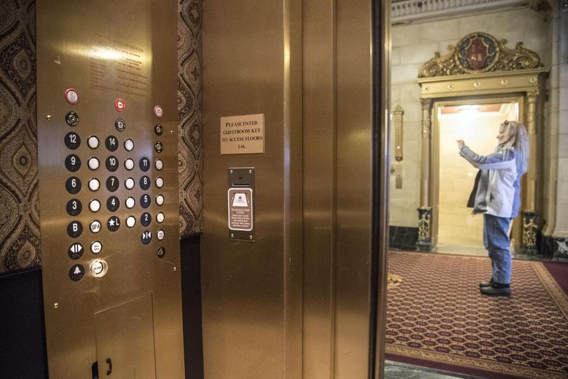 Linda Gallop, of Spokane, takes a cellphone picture of her out-of-town guests near an elevator in the Davenport Hotel Wednesday. There is no 13th floor button on the elevator panel. (Dan Pelle/SR photo)
