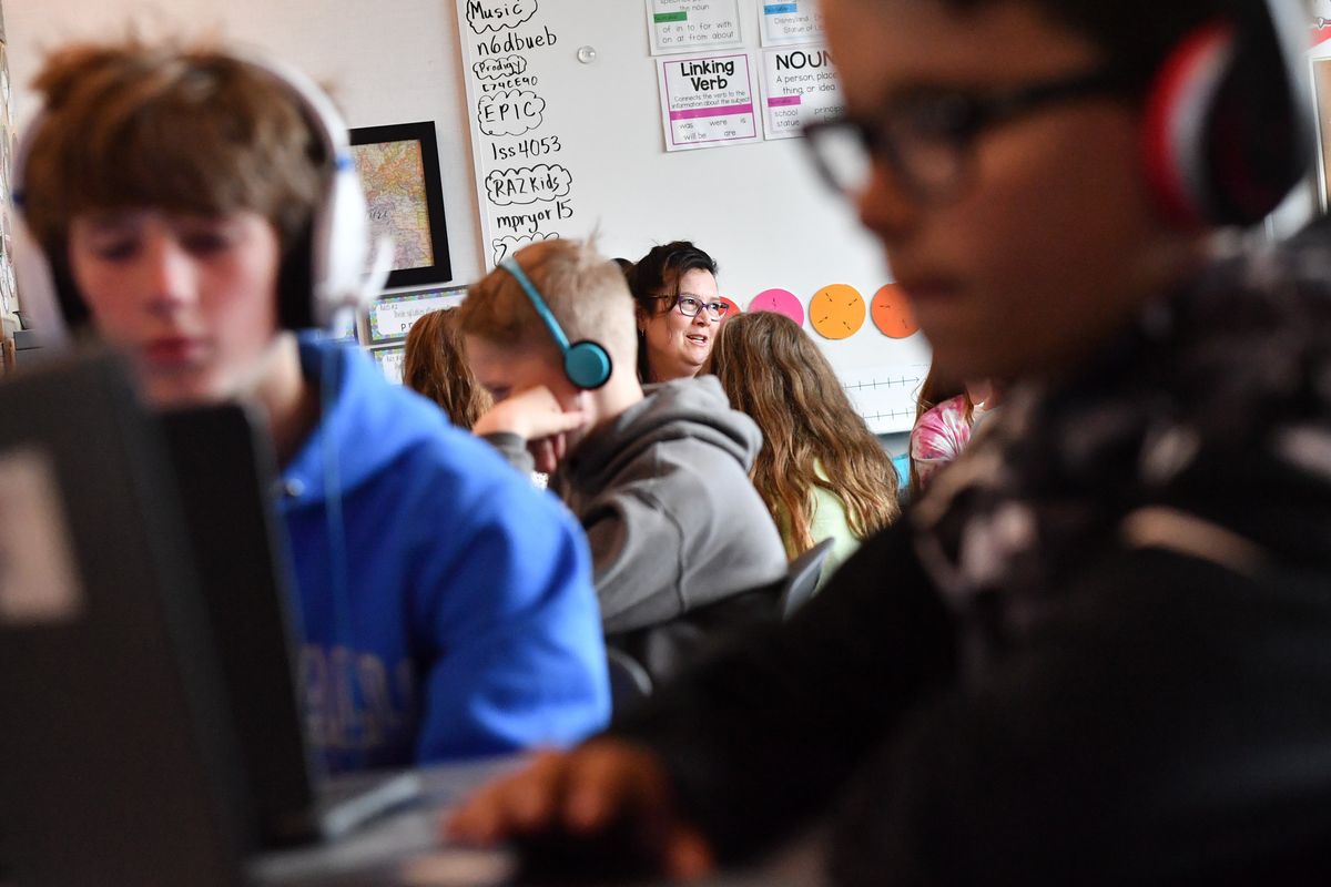 Melva Pryor, an elementary school teacher at Skyline Elementary, center, smiles as she helps her students through a lesson as a group works from laptops in the foreground on April 29 at Skyline Elementary.  (Tyler Tjomsland/The Spokesman-Review)