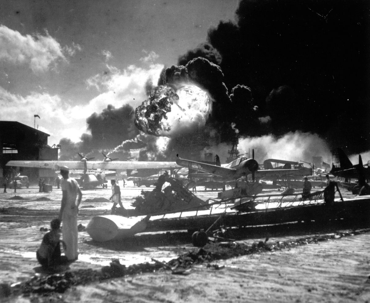 FILE - In this Dec. 7, 1941 photo provided by the U.S. Navy, sailors stand among wrecked airplanes at Ford Island Naval Air Station as they watch the explosion of the USS Shaw in the background, during the Japanese surprise attack on Pearl Harbor, Hawaii. (U.s. Navy)