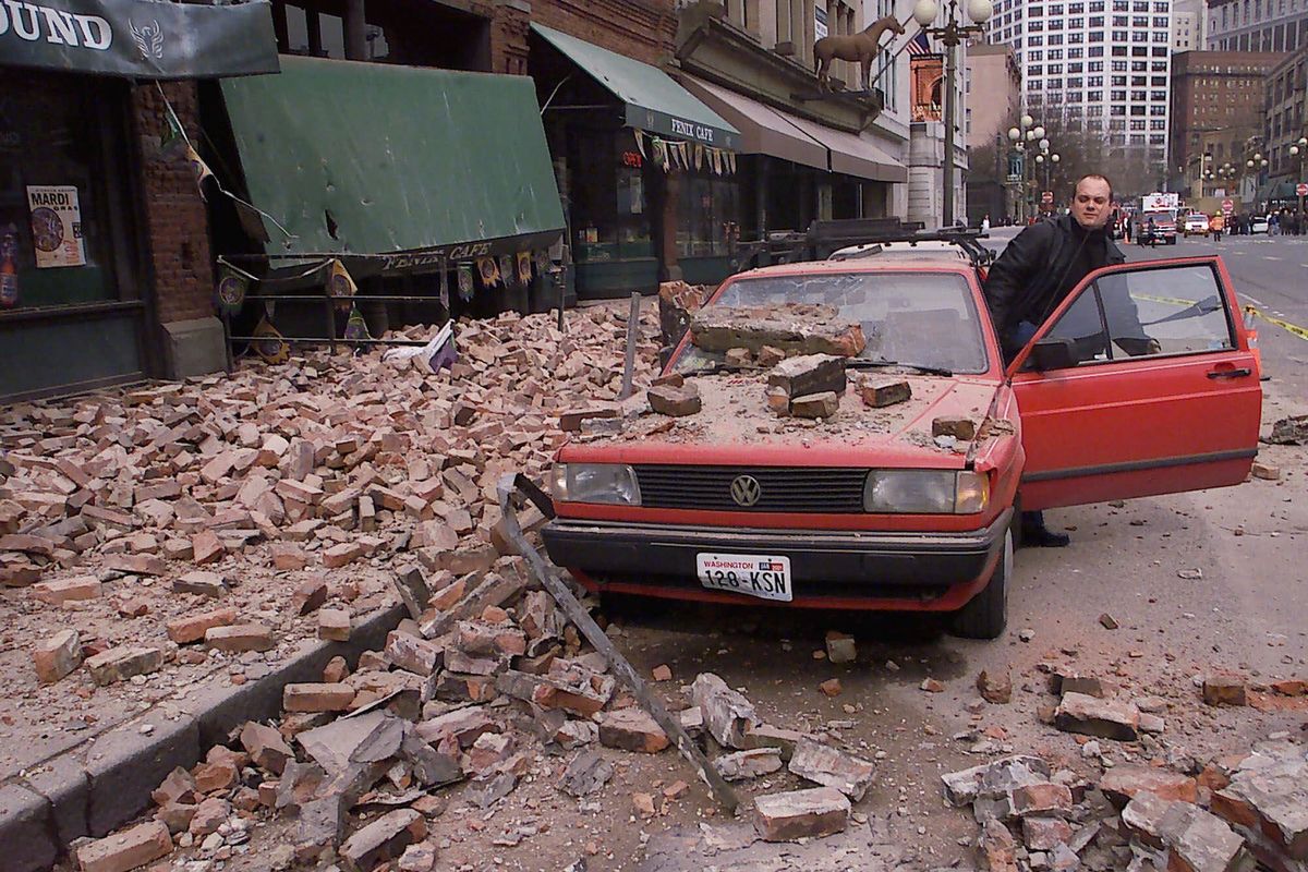 Paul Riek checks damage to his vehicle after the top half of a nearby building collapsed in downtown Seattle during the 6.8-magnitude Nisqually earthquake in February 2001.  (STEVAN MORGAIN)