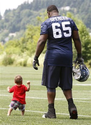 Seattle Seahawks center Chris Spencer walks with his son Jaxon, 11 months, following drills Wednesday at the team's voluntary minicamp in Renton, Wash. (Ted Warren / Associated Press)