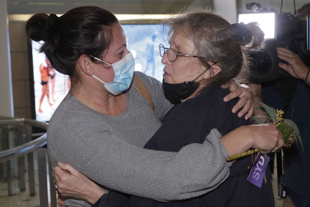 A woman, right, is embraced by. a loved-one after arriving on a flight from Los Angeles at Sydney Airport as Australia open its borders for the first time in 19 months in Sydney, Monday, Nov. 1, 2021. International travel will be initially restricted to Sydney