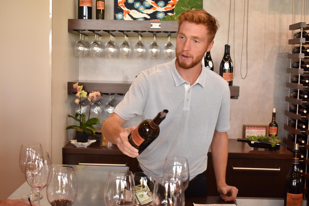 Ragan Schichtel, a tasting room associate, pours a bottle of wine for customers at Amavi Cellars in Walla Walla on Aug. 17. Schichtel was born and raised in the area. (Don  Chareunsy / The Spokesman-Review)