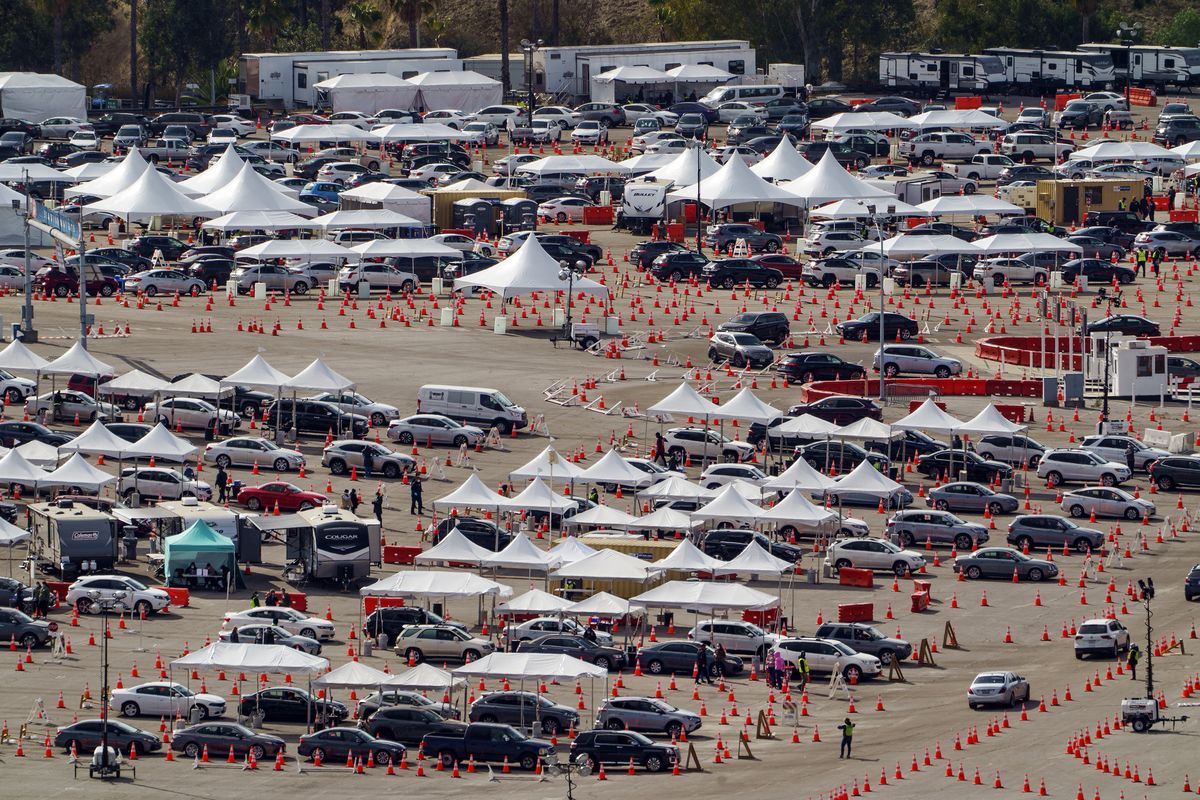 In this Jan. 27, 2021 photo, drivers wait in line at a mega COVID-19 vaccination site set up in the parking lot of Dodger Stadium in Los Angeles. One of the largest vaccination sites in the country temporarily shut down Saturday because dozen of protesters blocked the entrance, stalling hundreds of motorists who had been waiting in line for hours, the Los Angeles Times reported.  (Damian Dovarganes)