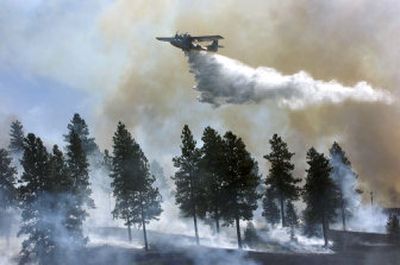 
A tanker drops water on the south side of a fire burning along Upriver Drive and Fruithill on Saturday. 
 (Dan Pelle / The Spokesman-Review)