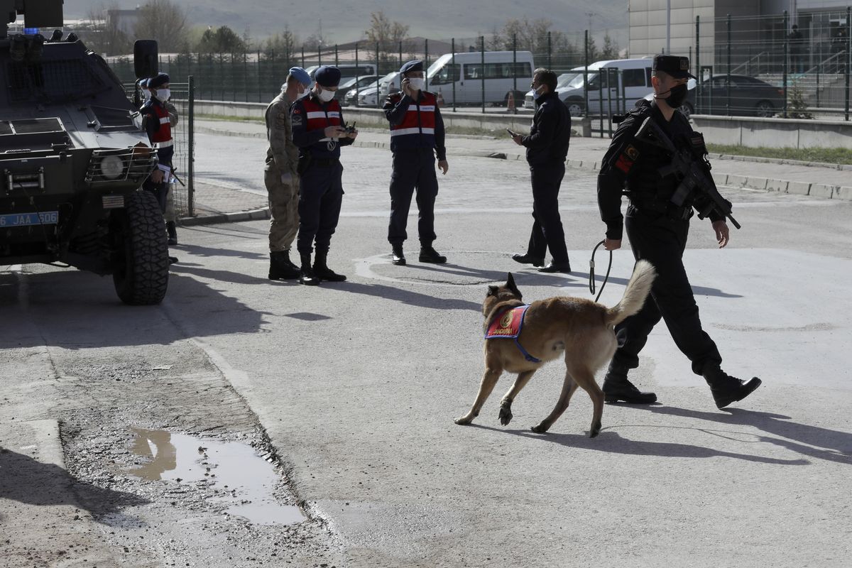 Soldiers stand at the entrance as people wait outside a courthouse before the trial of 497 defendants, in Sincan, outside the capital Ankara, Turkey, Wednesday, April 7, 2021. The court was expected to deliver a verdict in their trial for involvement in a failed coup attempt in 2016.  (Burhan Ozbilici)