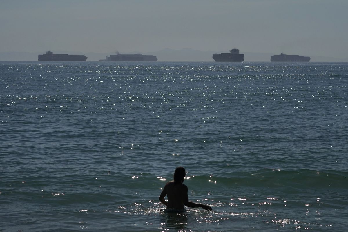 A man wades through the water at Seal Beach Calif., Friday, Oct. 1, 2021, as container ships waiting to dock at the Ports of Los Angeles and Long Beach are seen in the distance. California state lawmakers held a joint legislative hearing at the Capitol in Sacramento, Wednesday, Nov. 3, to discuss the supply chain disruptions. While congestion at the state