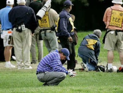 
Phil Mickelson, after a poor drive on the 18th hole, looks away as Tiger Woods hits the second shot from along a fence
 (Associated Press / The Spokesman-Review)