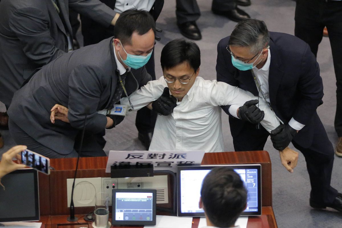 FILE - In this May 8, 2020, file photo, then pan-democratic legislator Eddie Chu, center, is taken away by security guards during a Legislative Council