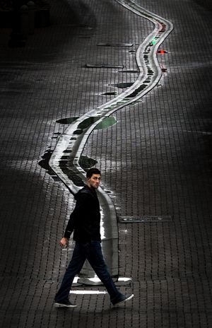 End of the line: A pedestrian walks Friday along Main Avenue past the mid-street gutter on Wall Street in downtown Spokane. (Colin Mulvany)