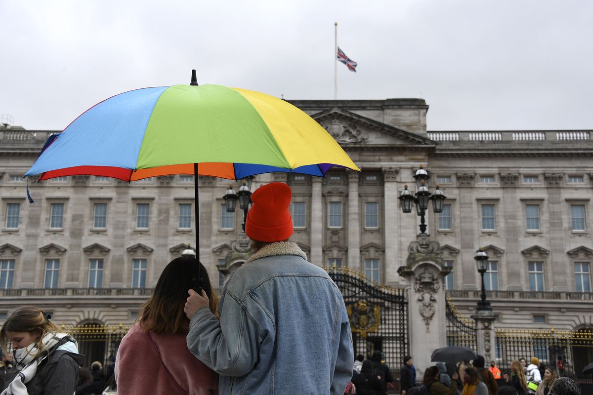 A couple under an umbrella look at the Union flag at half-staff over Buckingham Palace in London, a day after the death of Britain's Prince Philip, Saturday, April 10, 2021. Britain's Prince Philip, the irascible and tough-minded husband of Queen Elizabeth II who spent more than seven decades supporting his wife in a role that mostly defined his life, died on Friday.  (Alberto Pezzali)