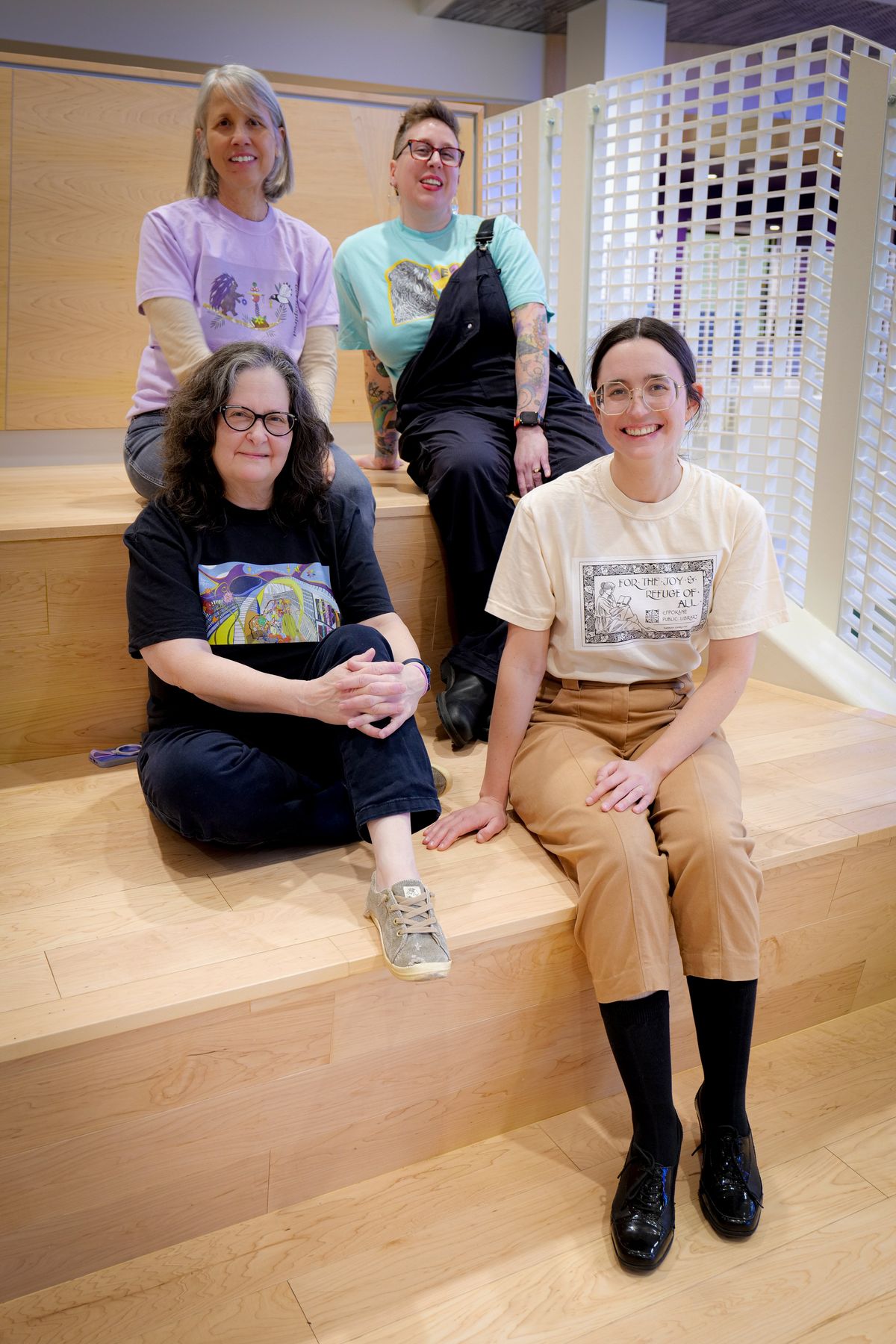 Artists, back left, Katie Creyts, Sarah Louise, and front left, Genie Maples and Hannah Charlton, sit on the reading steps of the Spokane Public Library