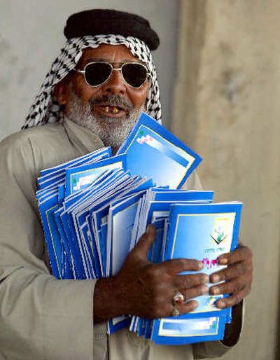 
An Iraqi food distributor carries copies of the draft constitution Tuesday before distributing them in the Sadr City neighborhood of Baghdad. The stakes for the United States are high in Saturday's constitutional referendum in Iraq. 
 (Agence France Presse / The Spokesman-Review)