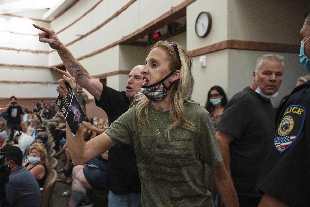 FILE - In this Aug. 12, 2021 file photo, protesters against a COVID-19 mandate gesture as they are escorted out of the Clark County School Board meeting at the Clark County Government Center, in Las Vegas. The nation