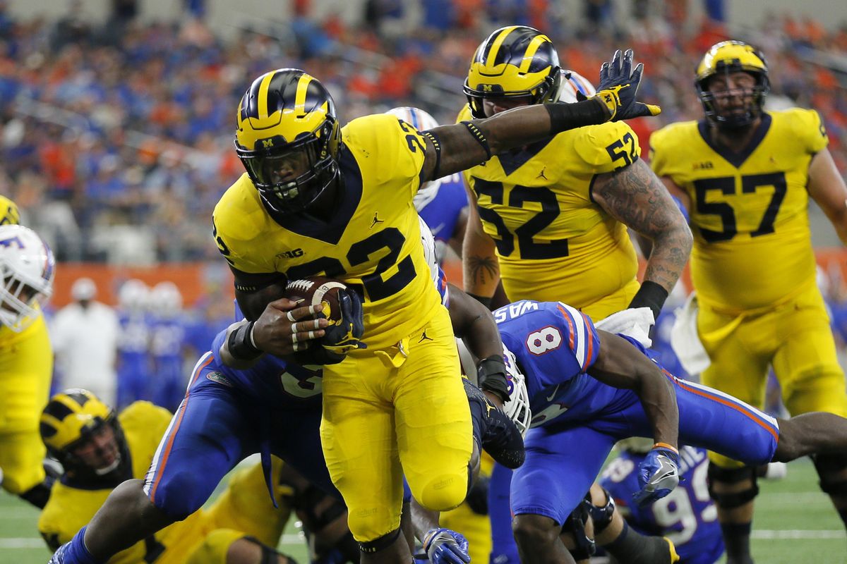 Michigan running back Karan Higdon (22) reaches the end zone for at touchdown on a running play after getting through Florida linebacker David Reese, left, and defensive back Nick Washington (8) in the second half of an NCAA college football game, Saturday, Sept. 2, 2017, in Arlington, Texas. (Roger Steinman / Associated Press)