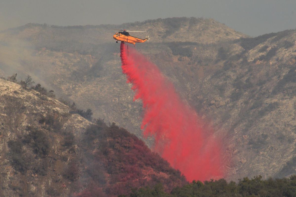 In this photo provided by the Santa Barbara County Fire Department, a Sikorsky S-61 drops fire retardant onto a hillside Friday, Dec. 15, 2017, in San Ysidro Canyon in Montecito, Calif. (Mike Eliason / Associated Press)
