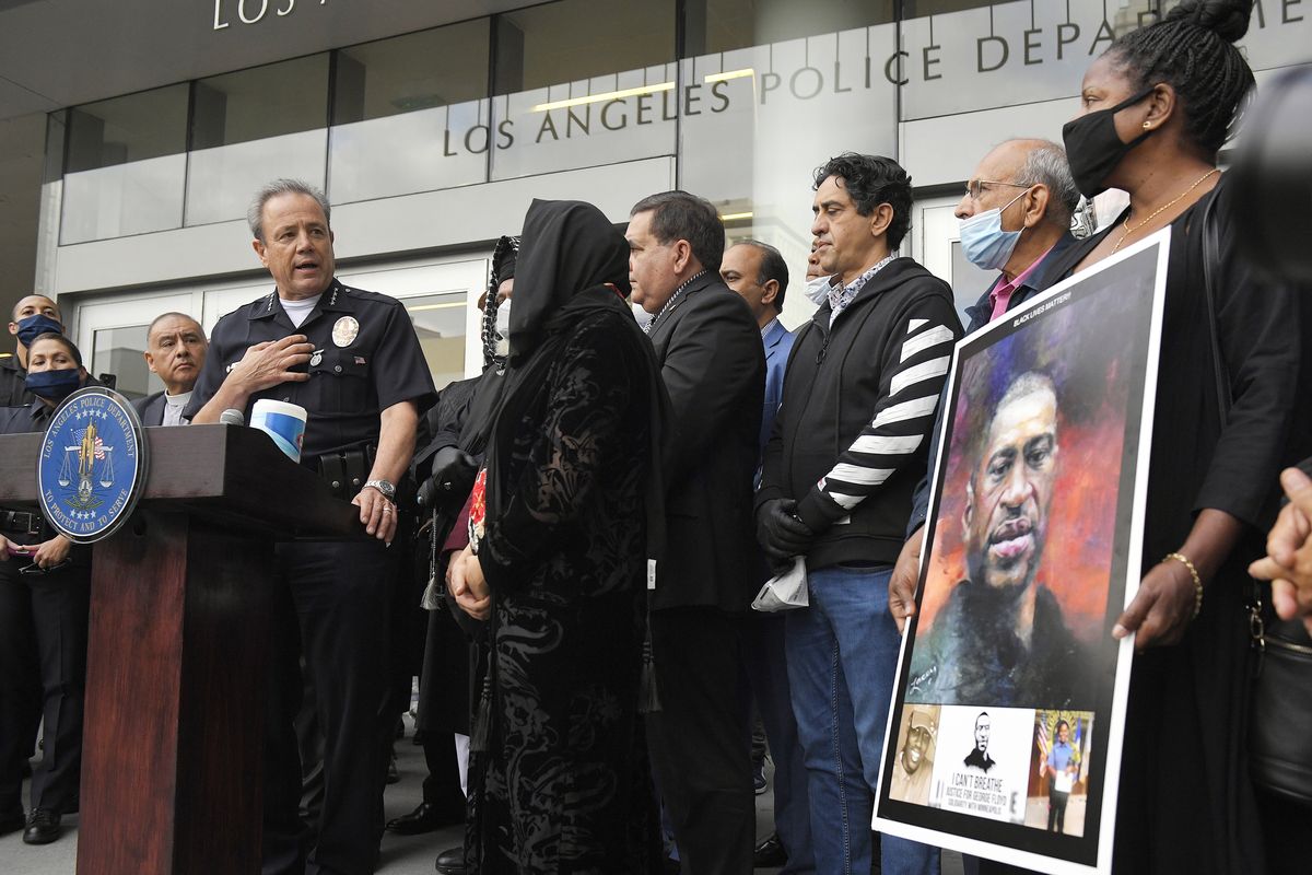 FILE - In this June 5, 2020, file photo, Los Angeles police chief Michel Moore, left, speaks as someone holds up a portrait of George Floyd during a vigil with members of professional associations and the interfaith community at Los Angeles Police Department headquarters in Los Angeles. The Los Angeles Police Department launched an internal investigation after an officer reported that a photo of Floyd with the words "You take my breath away" in a Valentine-like format was circulated among officers, according to a newspaper report. Moore said Saturday, Feb. 12, 2021, that investigators will try to determine how the image may have come into the workplace and who may have been involved, the Los Angeles Times reported.  (Mark J. Terrill)