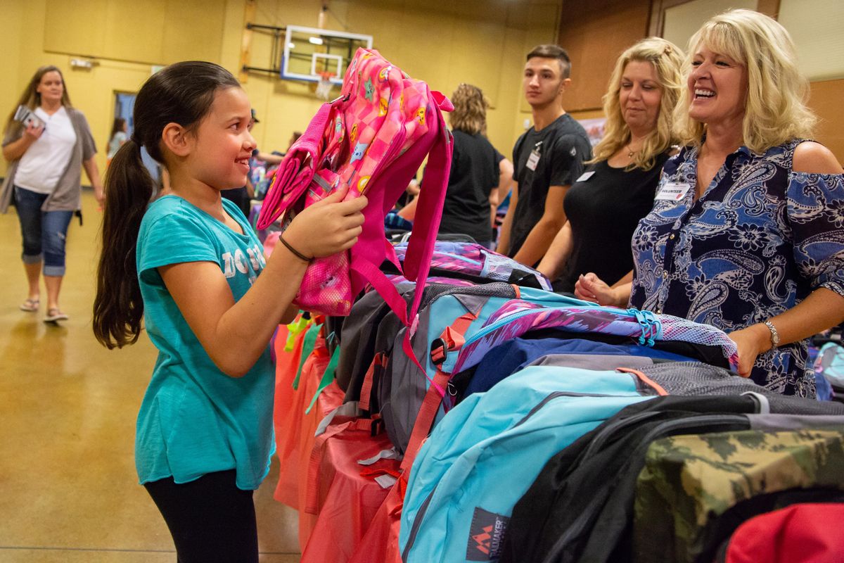 Third-grader Sanaia Gregerson receives a backpack at the Salvation Army backpack distribution in Spokane on the morning of Aug. 15, 2018. The line for the event began at 5 a.m. and 812 backpacks were distributed in the first hour after doors opened at 8 a.m., which is equal to 292 households that received donations. (Libby Kamrowski / The Spokesman-Review)