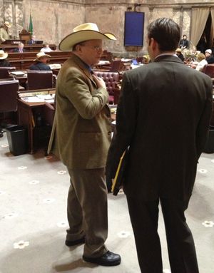 OLYMPIA -- Sen. Mike Padden, left, talks with Sen. Andy Billig Thursday on the floor of the Senate during debate on the National Cowboy Day resolution. (Jim Camden)