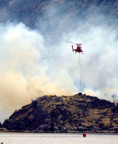 
A helicopter picks up water from the Columbia River on Tuesday while fighting the Beebe fire near Chelan Falls.
 (Associated Press / The Spokesman-Review)