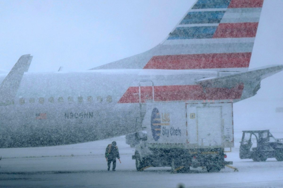 Snow falls on a ground crew working outside a parked plane on Thursday at Dallas Fort Worth International Airport in Grapevine, Texas. (LM Otero)