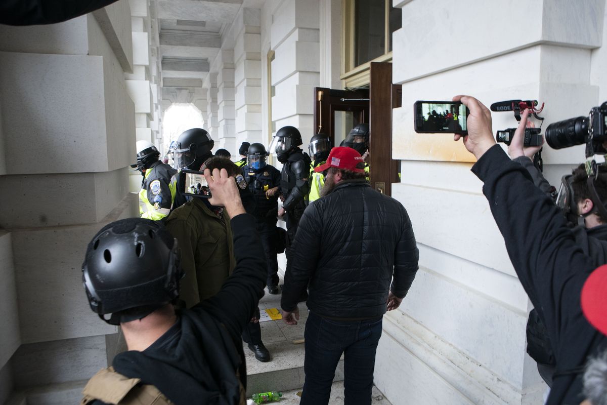 In this Jan. 6, 2021 photo, people record as Capitol police officers push back violent insurrectionists loyal to President Donald Trump U.S. Capitol in Washington.  (Jose Luis Magana)