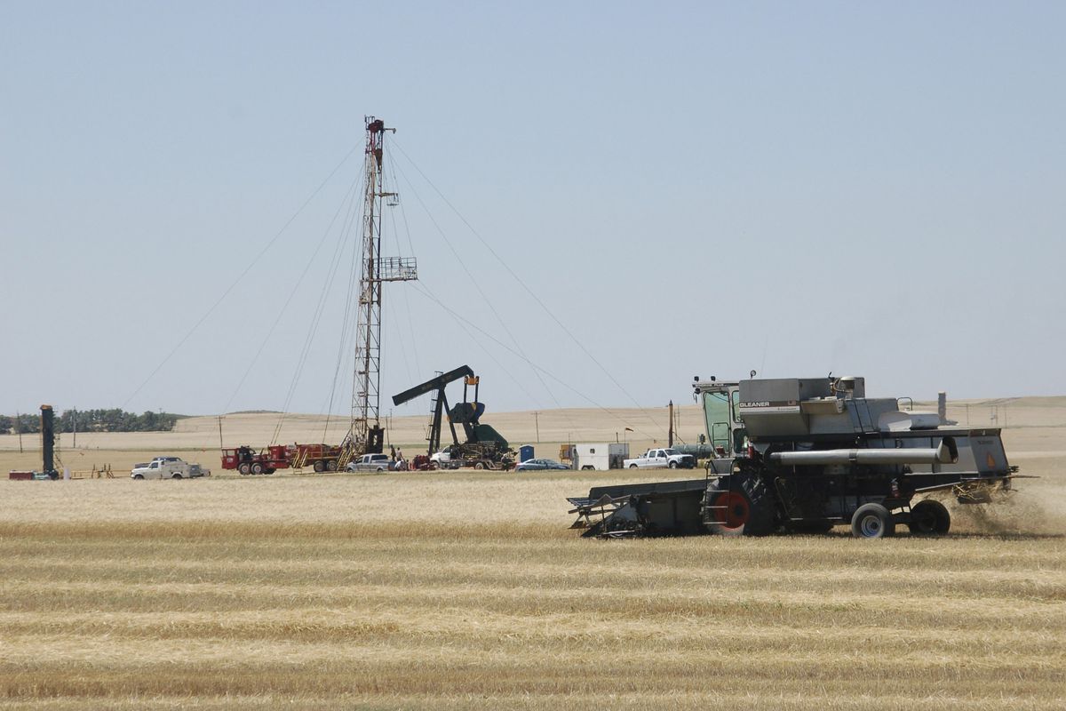 In this August 2008 photo, a combine cuts durum near an oil well in Tioga, N.D. Domestic production of oil is rising for the first time in two decades thanks to new drilling techniques that are opening up vast fields of previously out-of-reach oil in the western United States. (Associated Press)
