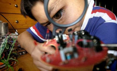 
Alex Lam-Niemeyer uses a magnifier to examine an electronic light-seeking bug he created last week in his Berkeley, Calif., home. Lam-Niemeyer he researches his book reports by scouring library stacks the same way students have done for generations. 
 (Associated Press / The Spokesman-Review)