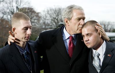 President  Bush kisses Marine Corps Lance Cpl. Marc E. Olson of Coal City, Ill., after talking to Marine Corps Lance Cpl. Patrick Paul Pittman Jr., left, of Savannah, Ga.,  on the South Lawn of the White House on Tuesday. Both Marines served in Iraq. Bush stopped to pose for a photograph with each after returning from West Point, where he had delivered a speech.  (Associated Press / The Spokesman-Review)