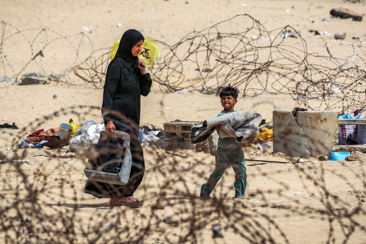 A woman and boy walk with belongings past barbed-wire fences as they flee from Rafah in the southern Gaza Strip on Saturday.  (AFP)