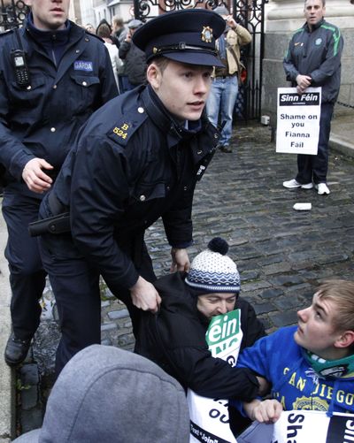 Irish police officers attempt to remove Sinn Fein protesters from inside the grounds of government buildings in Dublin, Ireland, on Monday.  (Associated Press)