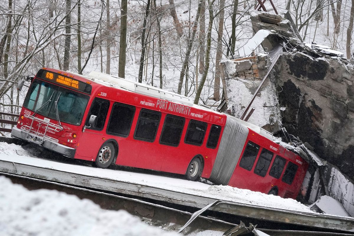 A Port Authority bus that was on a bridge when it collapsed Friday Jan. 28, 2022, is visible in Pittsburgh's East End. A two-lane bridge collapsed in Pittsburgh early Friday, prompting rescuers to rappel nearly 150 feet (46 meters) while others formed a human chain to help rescue multiple people from a dangling bus.  (Gene J. Puskar)