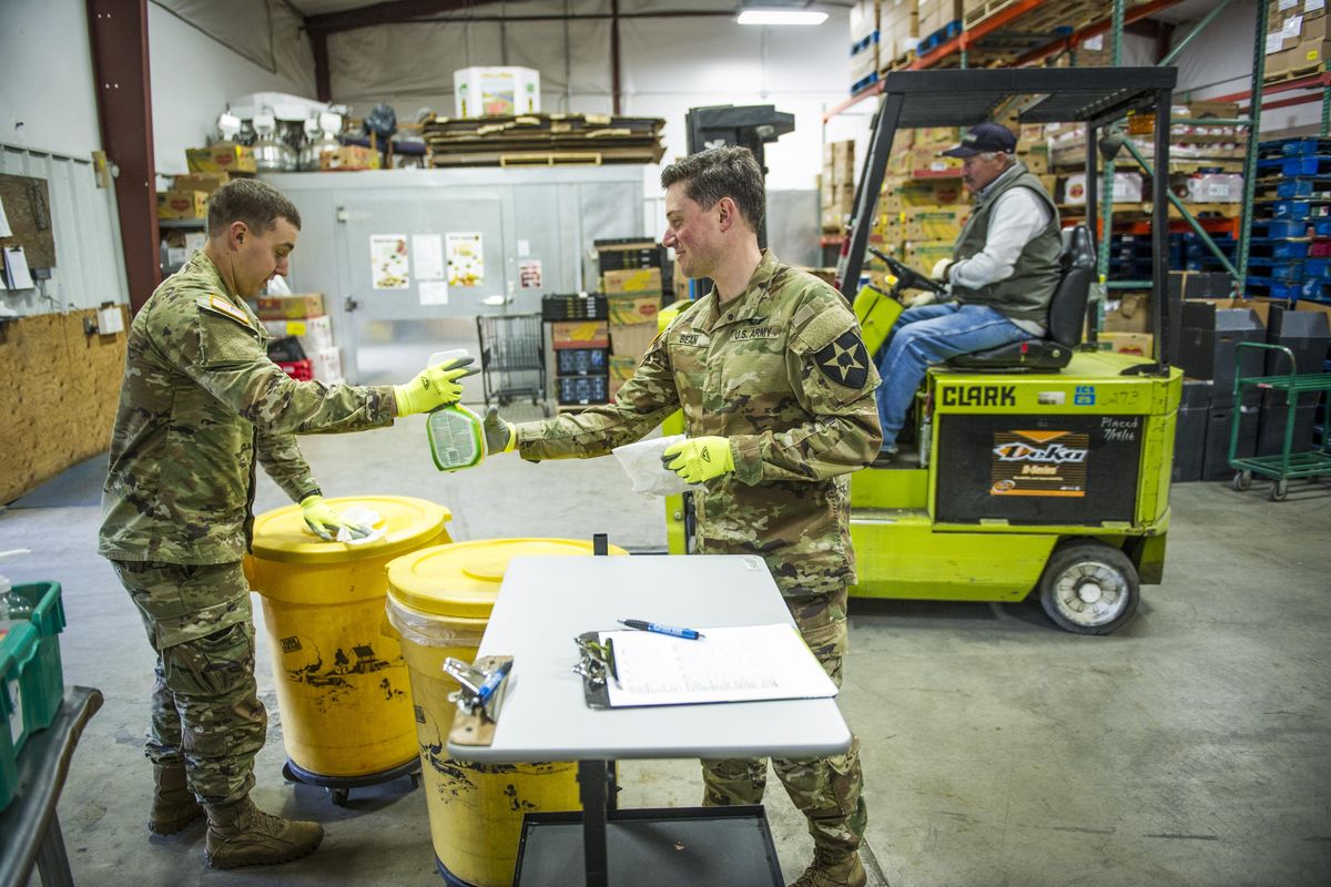 Washington National Guard 2nd Lieutenants  Brett Busch, left, and Ethan Bean set to work sanitizing highly used surfaces at the Blue Mountain Action Council food warehouse in Walla Walla, Wash., Thursday, April 2, 2020. The two were deployed from Spokane, Washington, a couple hundred miles to the north to help with coronavirus related issues. Inslee on Sunday activated to the National Guard statewide to respond to looting and other violence. (Greg Lehman / Walla Walla Union-Bulletin via AP)