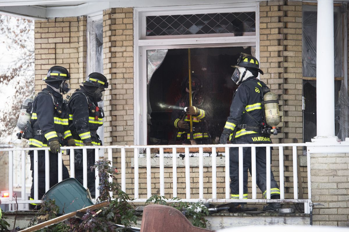 Spokane Fire Department firefighters mop up after a house converted into apartments at 903 W. Augusta Avenue caught fire Friday afternoon.  One person suffered burns in the blaze. (Colin Mulvany / The Spokesman-Review)
