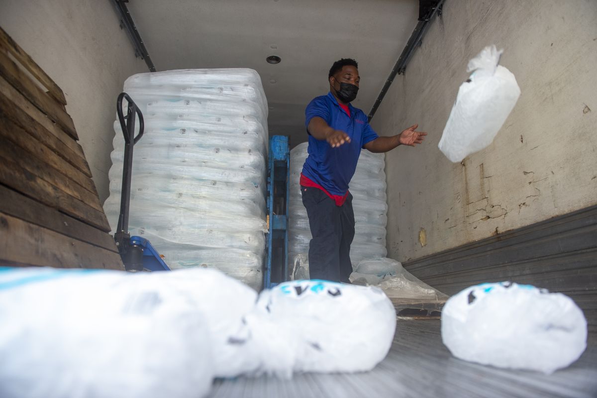 John Smith of Pelican Ice tosses bags of ice to the end of a truck Friday as he helps stock a gas station in Jefferson, La., as residents prepare for Tropical Storm Ida.  (CHRIS GRANGER)