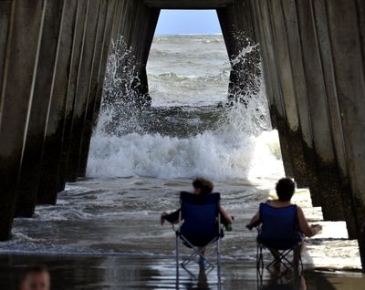 Visitors from Dahlonega, Ga., watch the surf crash into the pylons under the pier on Tybee Island, Ga., Wednesday as Hurricane Irene heads toward South Florida. (Associated Press)