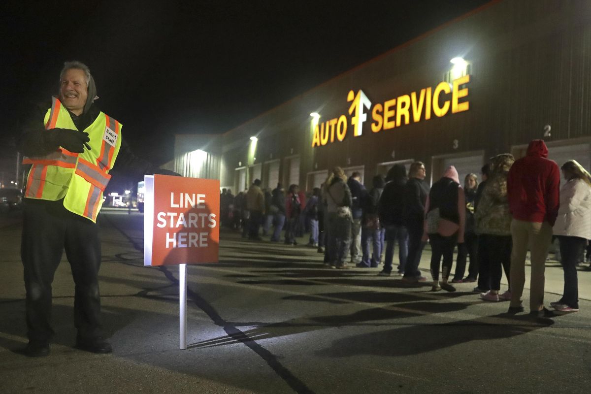 Larry Olsen assists shoppers waiting in line during the early morning hours of Black Friday at Fleet Farm on Friday, Nov. 29, 2019, in Appleton, Wis. (Wm. Glasheen / Associated Press)