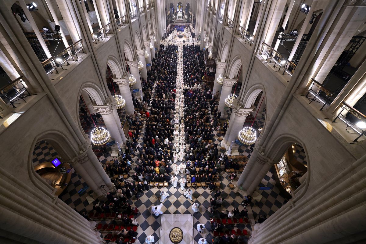 Members of the clergy walk towards the new main altar after the first Mass in the restored Cathedral on Sunday in Paris, France. Presided over by Archbishop Laurent Ulrich, the Mass gathered nearly 170 bishops from around the world, Parisian priests, heads of state and faithful attendees to celebrate.  (Pascal Le Segretain)