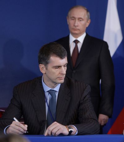 In this 2009 file photo, Russian Prime Minister Vladimir Putin, right, looks on as Mikhail Prokhorov signs an agreement during a Franco-Russian meeting in Rambouillet, France. Prokhorov, one of Russia's richest tycoons and the owner of the New Jersey Nets basketball team, said he will run against Putin in the March presidential election. (Alexei Druzhinin / Pool Ria Novosti)