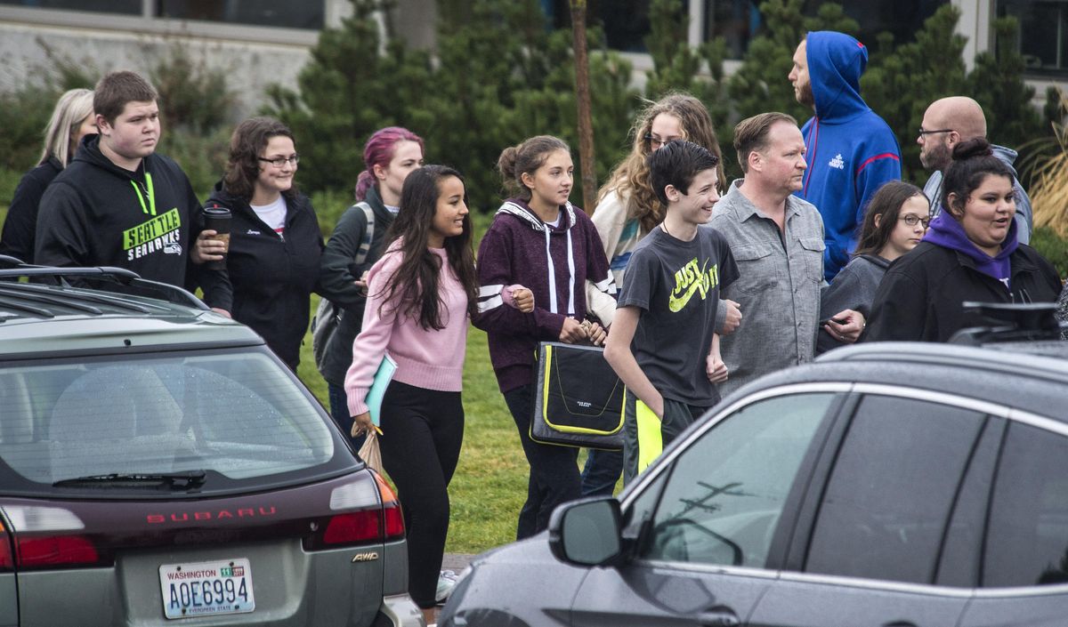 Freeman High School students walk arm-in-arm with parents, Monday, Sept. 18, 2017, as they re-enter the school to attend classes for the first time after a shooting left one student dead and three injured last week near Rockford, Wash. (Dan Pelle / The Spokesman-Review)