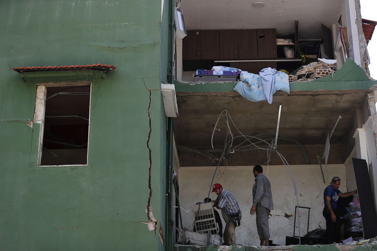 Workers remove debris from a house damaged by Tuesday