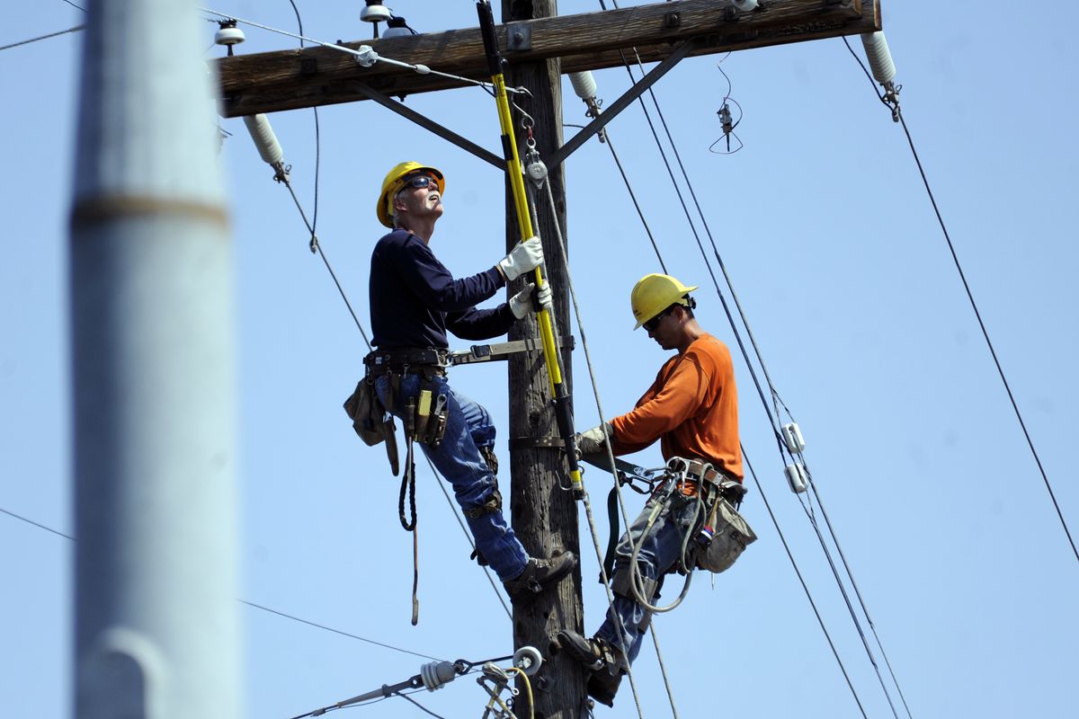 Avista Utilities linemen work on a power pole high above Division Street and Hawthorne Road on Sunday. Thousands of Avista customers remained without power a day after Saturday’s windstorm. At one point nearly 50,000 homes were without power. (Jesse Tinsley)