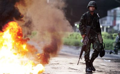 A Thai soldier walks past a fire set by anti-government demonstrators today in Bangkok, Thailand.  (Associated Press / The Spokesman-Review)
