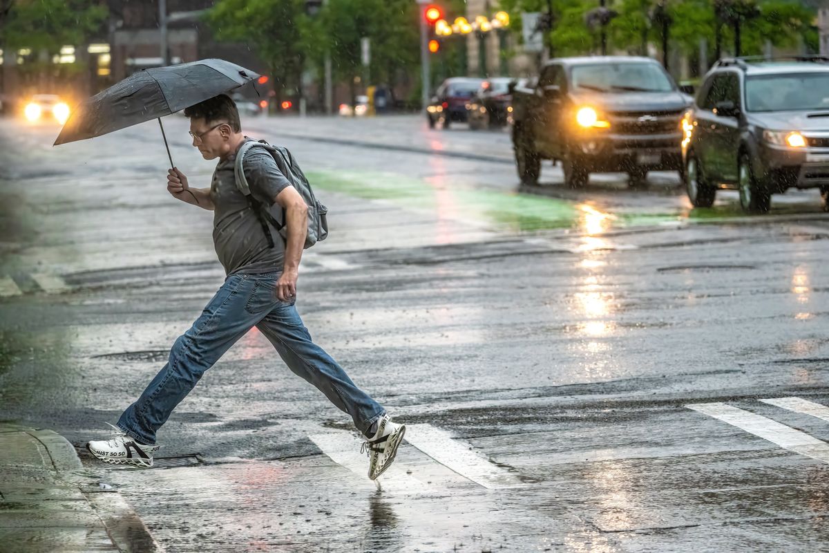 “I’m glad I packed an umbrella today,” said Chris Leamons after he hopped a puddle crossing Riverside Avenue in downtown Spokane on Thursday.  (COLIN MULVANY/THE SPOKESMAN-REVIEW)
