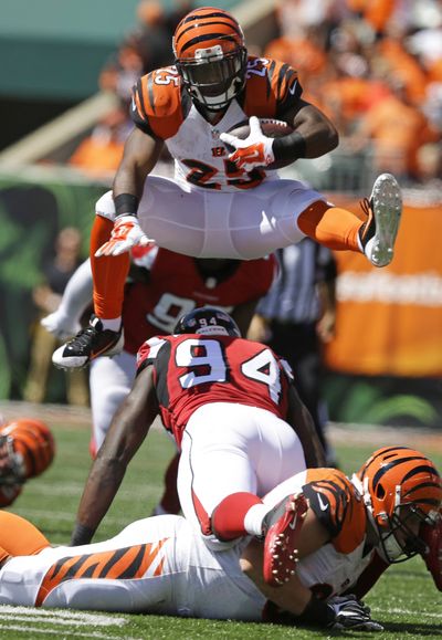 Cincinnati’s Giovani Bernard leaps over Atlanta’s Jonathan Massaquoi during the first half. (Associated Press)