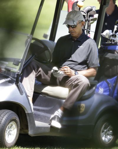President Barack Obama operates an electronic device Thursday while golfing on vacation on the island of Martha’s Vineyard. (Associated Press)